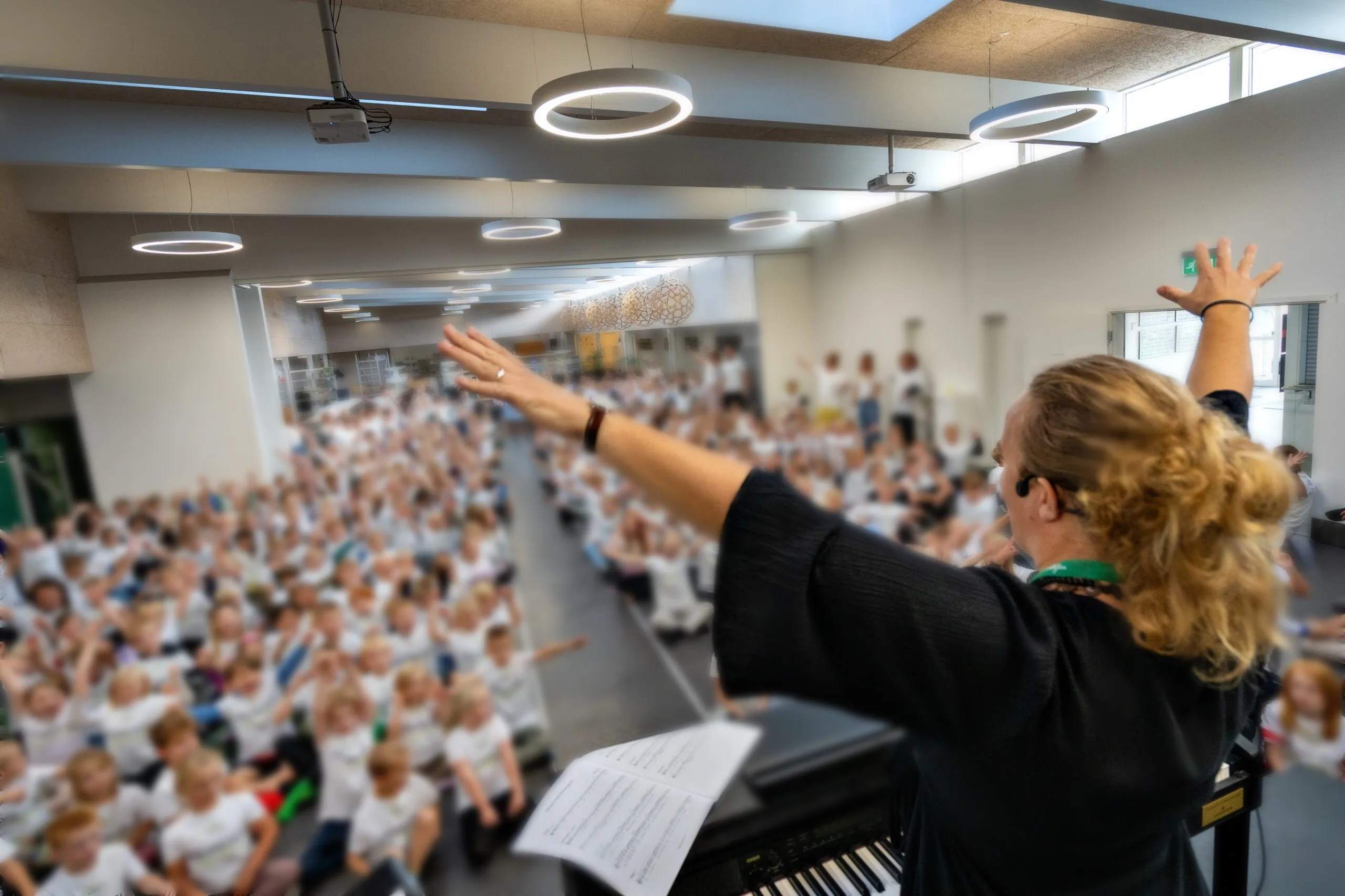 Signe holder korworkshop / korstævne med en stor sal fuld af glade børn